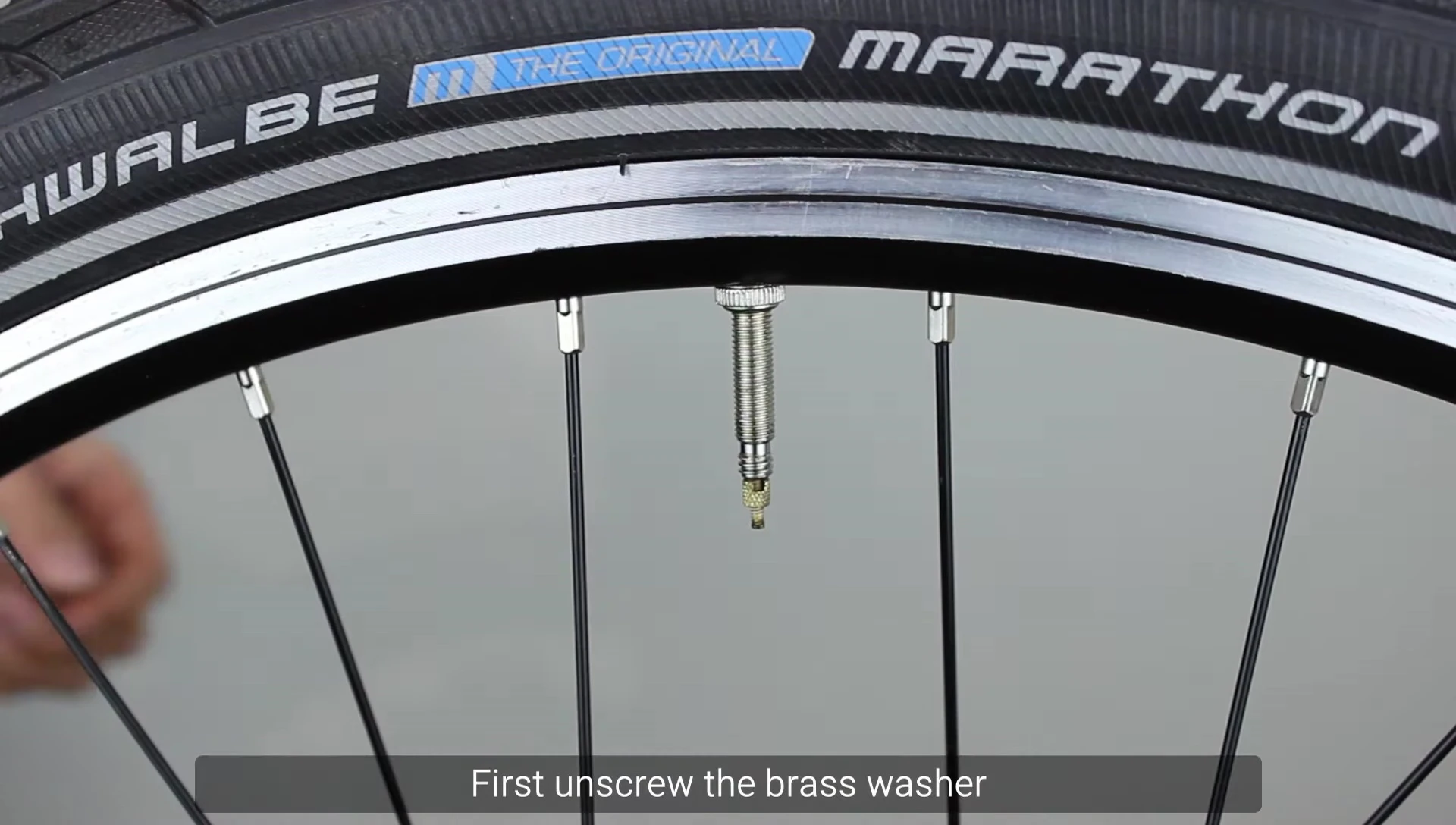 Unscrewing and depressing the brass washer on the Presta valve.