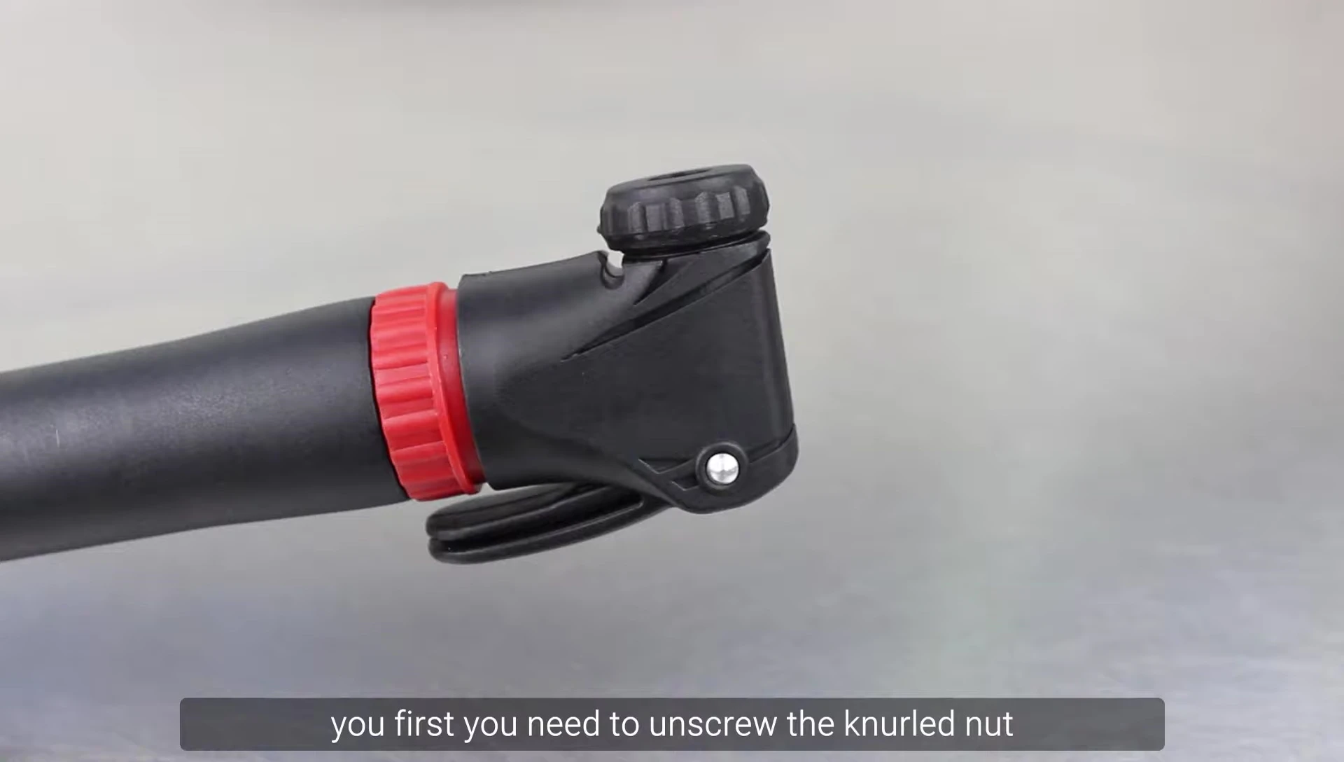 Close-up of unscrewing the knurled nut on a bicycle pump.