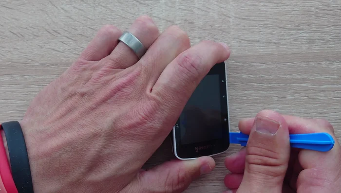 Carefully pry the screen away from the plastic base, starting from the top (near the Garmin logo) and working your way down. Be patient and avoid pulling on the ribbon cable.