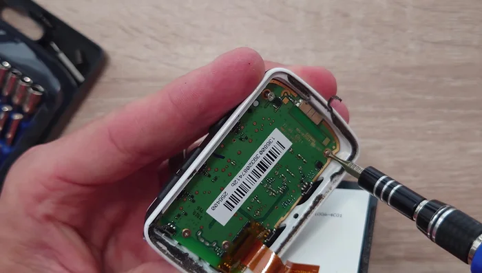 Gently remove the motherboard to reveal the battery. Use a plastic opening tool to help loosen the battery from its adhesive.