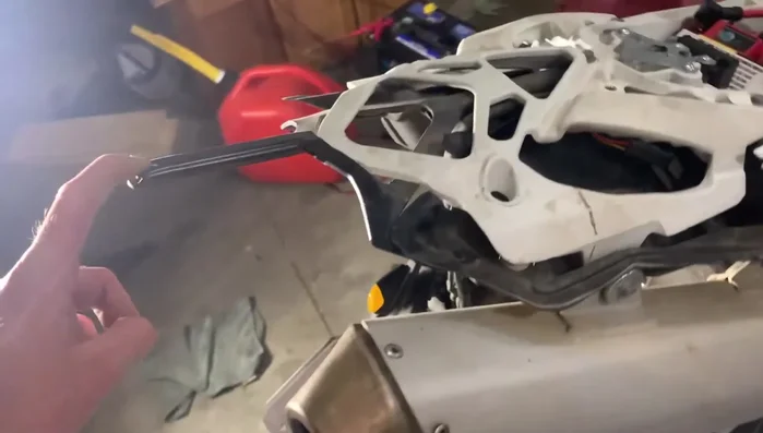 Straighten the bent support bracket underneath the fender using vice grips, an adjustable wrench, and a hammer.