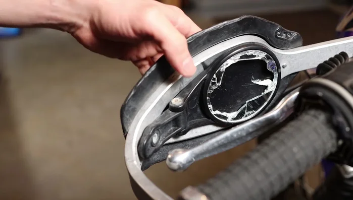 Use a flathead screwdriver to carefully remove the remaining shattered glass from the mirror assembly.