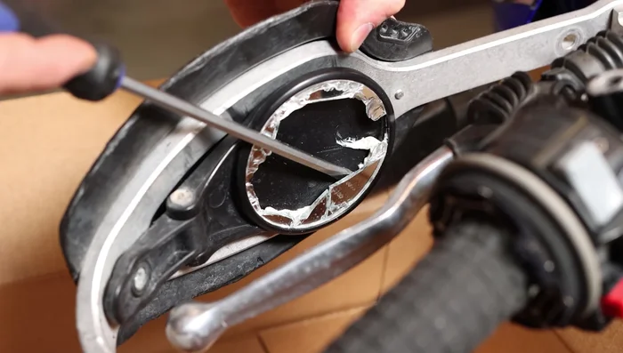 Use a flathead screwdriver to carefully remove the remaining shattered glass from the mirror assembly.