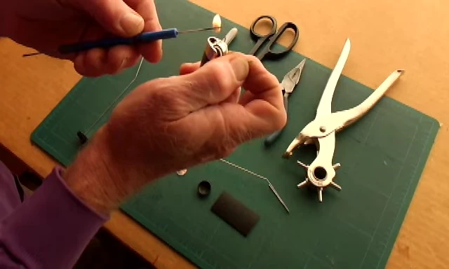 Heating up the sewing needle to make holes in the plastic.