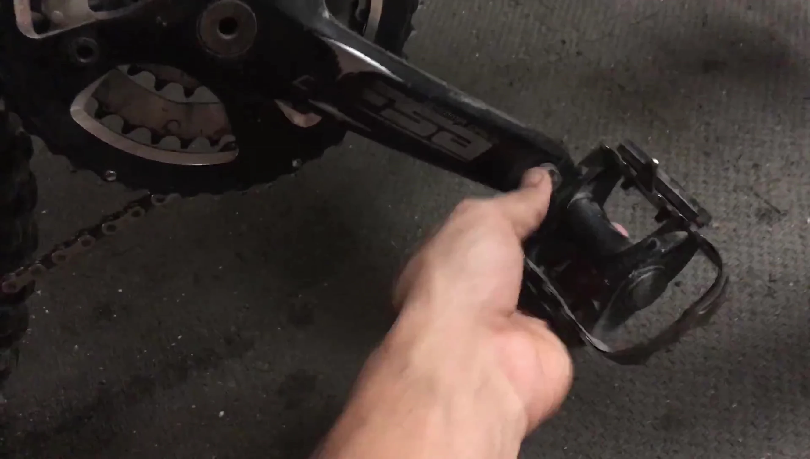The speaker is using a wrench to remove a pedal from the bike.